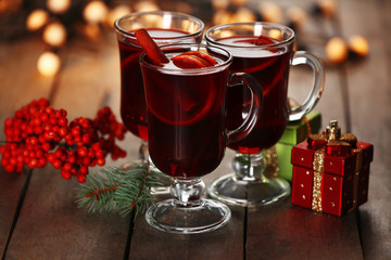 Mulled wine with spices and Christmas tree on wooden background