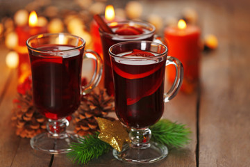 Mulled wine with spices and Christmas tree on wooden background
