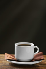 Cup of coffee and coffee grains on wooden table, on gray background
