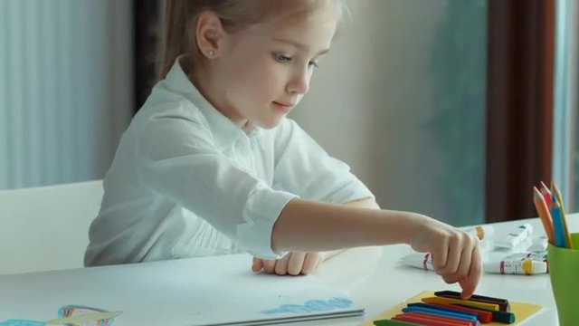 Child painting a bird. Girl looking at camera