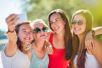 Focus on four girlfriends taking selfies on a smartphone 