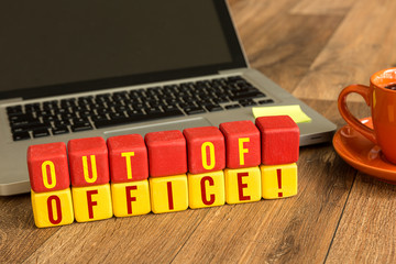 Out of Office written on a wooden cube in a office desk