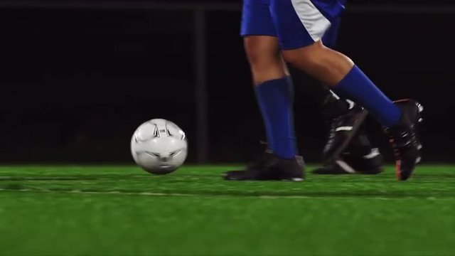 Close up of soccer players dribbling down the field at night
