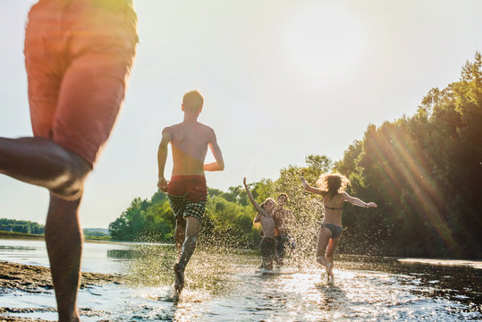 backlit shoot, back view of a teenagers running in water.flare 