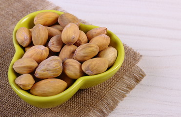 Pistachio nuts in bowl on white wooden table, healthy eating