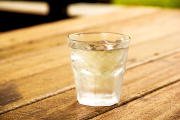 glass of clear alcohol on wooden table