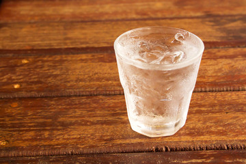 glass of clear alcohol on wooden table