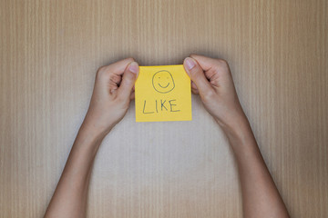 Like us on facebook concept using a hand holding a piece of pape