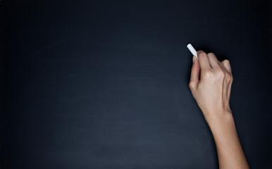 The human hand starts writing with chalk on a clean blackboard
