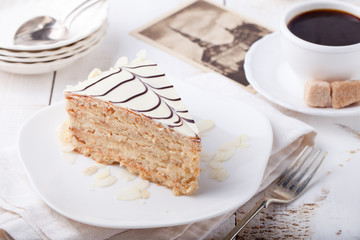 Traditional Hungarian Esterhazy cake with coffee cup and vintage postcards .