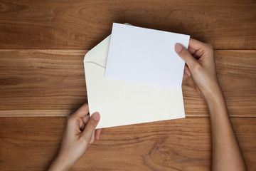 A female(woman) hand hold(open) a envelope and post card on the