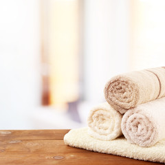 Rolled bath towels on wooden table in bathroom