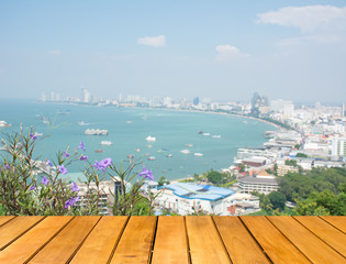wooden table with Pattaya City and sea and flower blurred  in ba