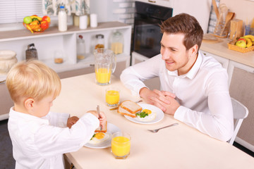 Obraz na płótnie Canvas Attentive dad watches his son eating.