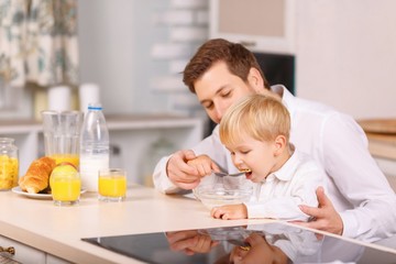 Obraz na płótnie Canvas Dad feeds his small son with cereal.