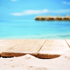 Fototapeta na wymiar Sand with wooden planks on sea background