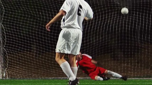 A soccer player making a penalty kick past the goalkeeper
