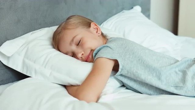 Child sleeping in a bed and smiling in his sleep