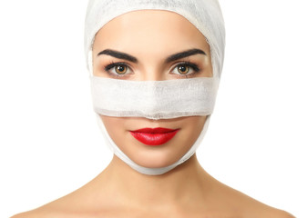 Young beautiful woman with a gauze bandage on her head and nose, isolated on white, close-up