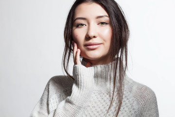 Obraz premium Pretty smiling woman with clean skin in white fluffy sweater on a white background