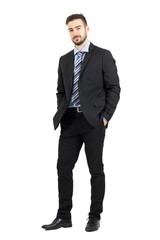 Young confident bearded business man in suit looking at camera.  Full body length portrait isolated over white studio background. 