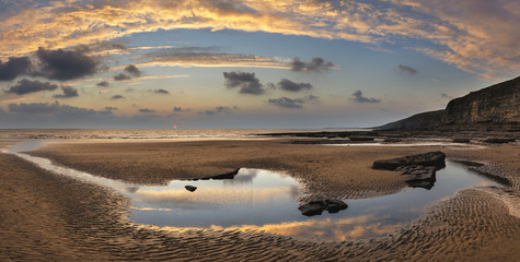 Stunning vibrant panorama sunset landscape over Dunraven Bay in