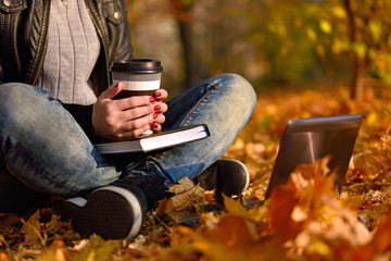 girl with coffee sitting in park