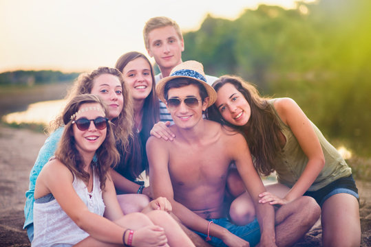 trendy teenagers on the beach at sunset, holidays, friendship