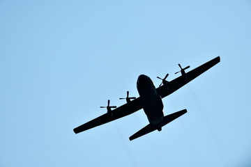silhouette of hercules transport plane against the blue sky