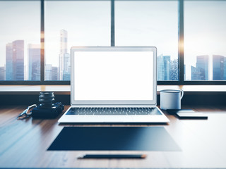 Generic laptop on the workspace with panoramic windows.  City at sunrise in a background. 3D rendering