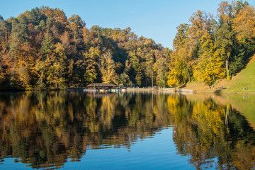 Fototapeta na wymiar Boat floating on Trakoscan lake in Zagorje, Croatia, season, autumn, Reflection of trees on water 