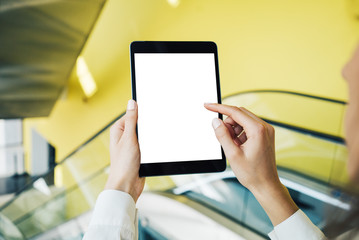 Blank tablet holding in woman hands on the blured background. Horizontal