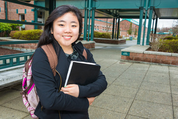Smiling Female Student on Campus with Book and Backpack