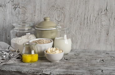 Ingredients for baking - flour, milk, butter, eggs on a light wooden table. Free space for text.  Food background