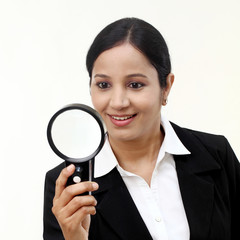 Young businesswoman looking through a magnifying glass