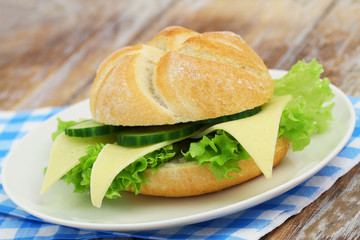 Freshly baked bread roll with cheese, lettuce and cucumber

