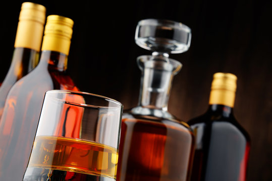 Bottles of assorted alcoholic beverages and glass of whisky