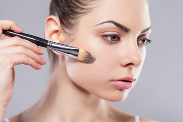 Beauty girl with makeup brushes. Perfect smooth skin.Applying makeup.Beautiful young woman holding...