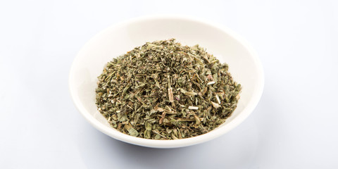 Dried lemon balm in white bowl over white background