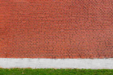 Red brown stone wall with green grass at the bottom edge.