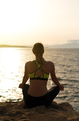Fototapeta na wymiar Young woman practicing yoga near the sea.