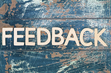 Word feedback written on rustic wooden surface
