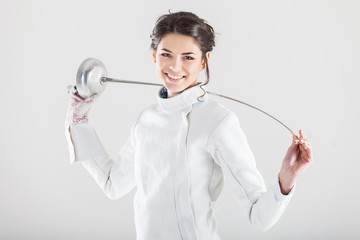 Portrait of woman wearing white fencing costume practicing with the sword
