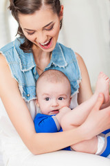 Happy family laughing faces, mother holding adorable child baby boy, smiling and hugging