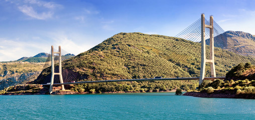 Obraz premium modern suspension bridge across river Luna and reservoir Los Bar