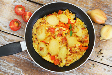 Omelette with potatoes, onions, red pepper and sweetcorn in frying pan
