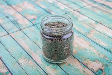 Dried lemon balm leaves in mason jar over wooden background