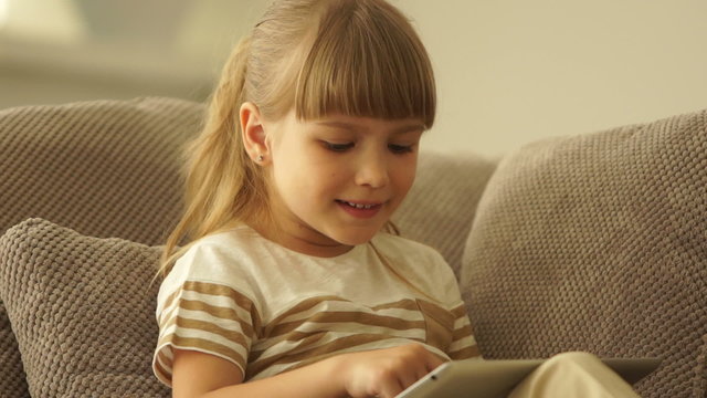 Cute girl playing on the tablet and smiling