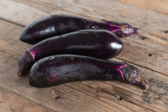Purple eggplants on wooden background.