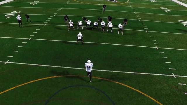 A football player punts the ball during a game, view from above
